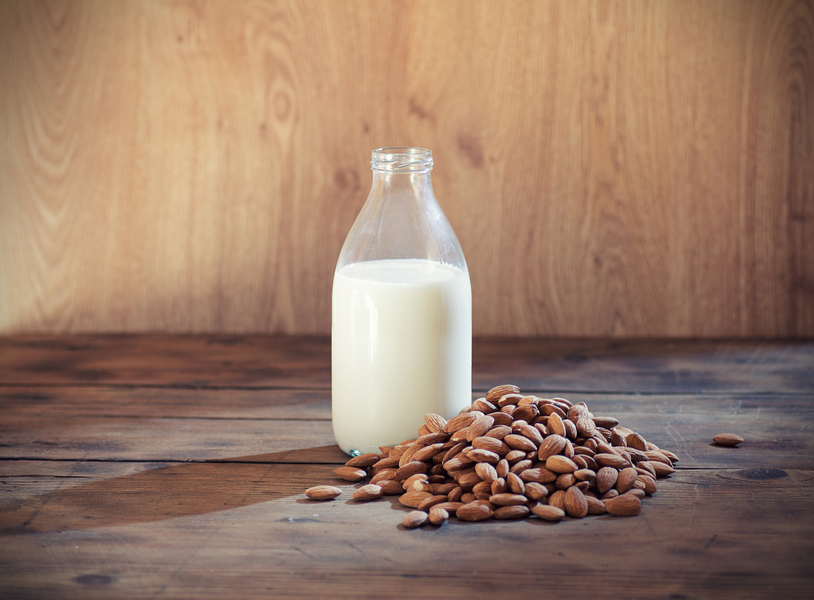 Almond milk in bottle with almonds